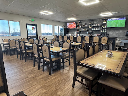 El Mariachis Liberty Hill Interior of El Mariachis Liberty Hill restaurant with rows of dining tables, cushioned chairs, wood-look flooring, and a full-service bar.